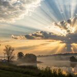 Cenário espiritual inspirador ao amanhecer com luz suave atravessando as nuvens sobre uma paisagem serena
