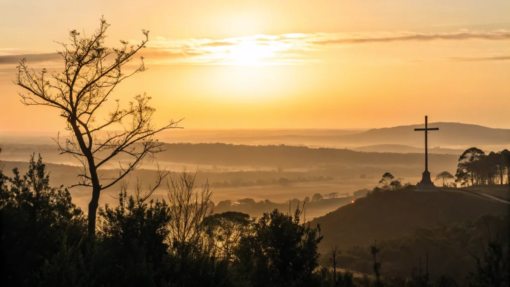 Imagem de um nascer do sol sobre uma paisagem tranquila com uma cruz em silhueta.
