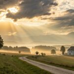 Paisagem campestre ao amanhecer com luz dourada e igreja ao fundo, representando fé e recomeço sob a graça de Deus
