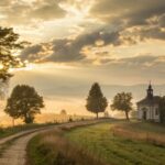 paisagem serena ao amanhecer com luz dourada e uma capela entre árvores, simbolizando fé e recomeço